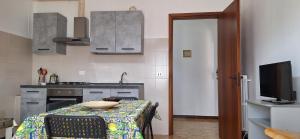 una cocina con una mesa y una cocina con un televisor en Luminoso appartamento nel cuore del Salento, en Campi Salentina