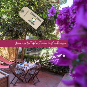 a table with two chairs and purple flowers at Il Giardino di Ada Ground Floor Studio with AC and Patio in Monterosso al Mare