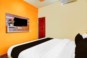 a bedroom with a white bed with an orange wall at HOTEL O UTSAV STAY in Jālahalli