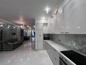 une cuisine avec des armoires blanches et un salon dans l'établissement на ПЛЯЖЕ Отрада, Французский бульвар Просторный 2 комн Luxury апартамент , центр ЖК Париж, à Odessa
