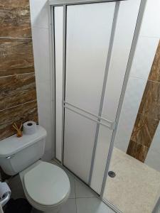 a bathroom with a toilet and a glass shower door at Apartamento Ideal Climatizado con Encanto Cultural in Buga +14 photos