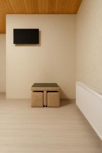 un banco en una habitación con TV en la pared en HOTEL RANCHO UPLISTSIKHE სასტუმრო რანჩო უიფლისციხე, en Uplistsikhe