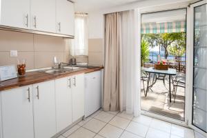 a kitchen with white cabinets and a view of a patio at D&D Holiday Studios in Potos +40 photos