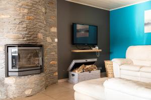 a living room with a stone fireplace with a tv at l'hôt'antique in Vielsalm