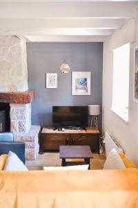a living room with a couch and a television at Les Gîtes du Vallon du Trunvel in Plonéour-Lanvern