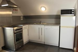 eine Küche mit weißen Geräten und einem Waschbecken in der Unterkunft Résidence Brise de Mer - 3 in Port Nayalo