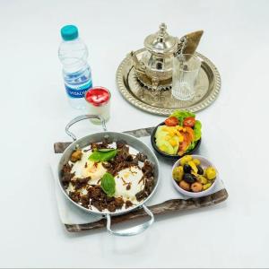 a table with a pan of food and two plates of food at Hotel Maram in Tangier