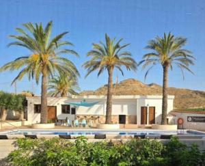 une maison avec des palmiers et une piscine dans l'établissement Cortijo La Cueva, à Arboleas