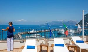 a woman standing on a balcony looking at the ocean at Relais Maresca Luxury Small Hotel & Terrace Restaurant in Capri
