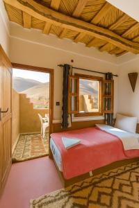a bedroom with a bed and a large window at Auberge la belle vue dades in Akhendachou nʼAït Ouffi