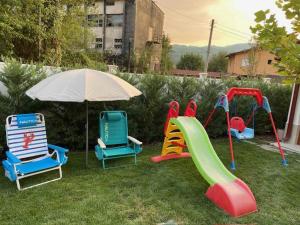 a playground with chairs and a slide and an umbrella at Villa Popovi in Simitli