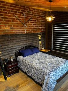 a bedroom with a bed and a brick wall at Cabaña Rústica in Natabuela