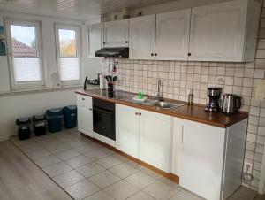 eine Küche mit weißen Schränken und einer Spüle in der Unterkunft Ferienwohnung Nordlicht in Hage + 17 Fotos
