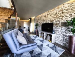een woonkamer met een blauwe bank en een stenen muur bij Refúgio da Nau in Vila do Conde