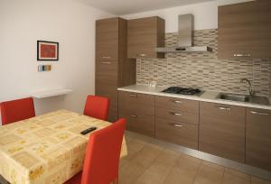 a kitchen with a table with red chairs and a sink at B&B Arena Casa Papardo in Messina