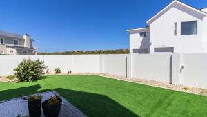 a backyard with a white fence and a lawn at Wine Not Relax in Yzerfontein