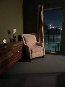 a chair and a dresser in a room with a window at The Jefferson Suite in Eagle Pass