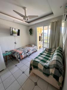 a bedroom with two beds and a table and a ceiling fan at Apartamento com churrasqueira em jurerê in Florianópolis
