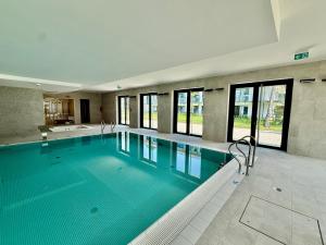 a large swimming pool with blue water in a building at Rezydencja Niechorze 124 z Ogródkiem, Basenem i SPA Gratis - 5D Apartments in Niechorze
