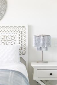 Dormitorio blanco con cama y mesita de noche con lámpara en Beachfront Haven Magenta, en Magenta