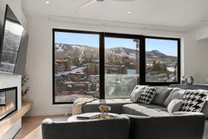 een woonkamer met een bank en grote ramen bij Modern 2 Bedroom Ski In&Out Condo 05 in Snowmass Village