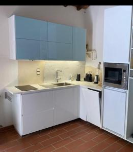 a white kitchen with a sink and a microwave at 2 Br,1bath with 2 AC units, garden apt in Chianti! in La Collina