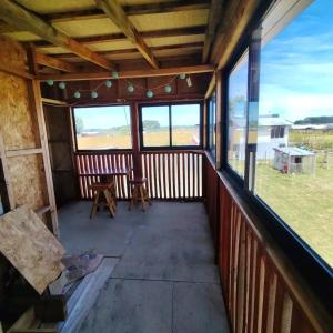 Un porche cubierto con ventanas, mesa y sillas. en Cabañamymemprende, en La Unión