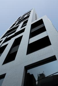 a tall white building with black windows at Shibuya Granbell Hotel in Tokyo