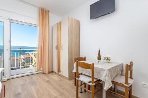 a dining room with a table and a large window at Rosemary Apartments in Duće