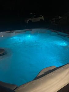 ein großer Pool mit blauem Wasser in der Nacht in der Unterkunft Charming Farmhouse w King Bed Hot Tub & EV Charger 