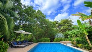 a swimming pool with chairs and an umbrella at Senda Beach House Tayrona in Buritaca