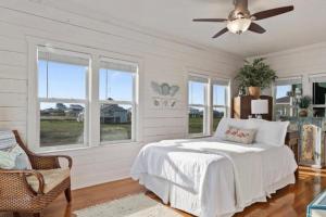 a white bedroom with a bed and windows at Paradise Beachfront Firepit Couples Retreat in Caplen