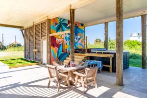 un patio avec une table et des chaises et une fresque murale dans l'établissement Beachfront 4BR - Tiki Bar, Yard Games, Pet-Friendly, à Gilchrist
