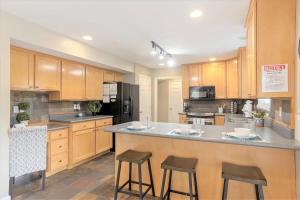 a kitchen with wooden cabinets and a large island with bar stools at Union Duplex in Salt Lake with Hot Tub and Park in Midvale