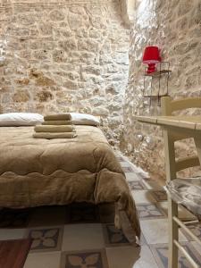 une chambre avec un lit et un mur en pierre dans l'établissement Liuzzi, à Martina Franca