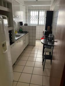 een kleine keuken met een tafel en een kleine keuken met een koelkast bij Apartamento Central Edifício Vale do Reno BC in Balneário Camboriú