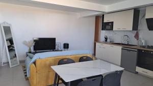 a living room with a kitchen and a table with chairs at La Kaz Héliconias in Le Tampon