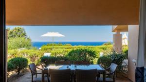 a table with chairs and an umbrella on a patio at Li Chessi Blu Villetta Familiare con Piscina in Costa Paradiso
