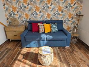 - un canapé bleu avec des oreillers colorés dans le salon dans l'établissement Studio TY PASSE-TEMPS, à Saint-Pierre-Quiberon