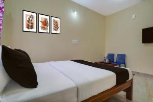 1 dormitorio con 1 cama y 3 cuadros en la pared en Hotel O Kalpatharu Boarding and Lodging, en Tyāmagondal