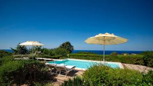 a swimming pool with two chairs and an umbrella at Li Chessi Blu Villetta Familiare con Piscina in Costa Paradiso