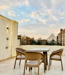 una mesa y sillas en un balcón con pirámides en The Pyramid Vault View INN, en El Cairo 34 fotos más