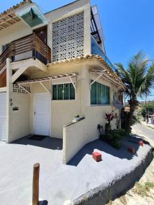 a white house with a palm tree in front of it at Casa Familiar 2 quartos em Búzios in Búzios