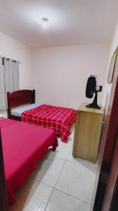 une chambre avec deux lits et une télévision sur une table dans l'établissement Casa de Férias do Ferreri Cabo Frio Próx Ponte Quebrada Rio São João, à Cabo Frio