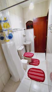 une salle de bains avec deux toilettes et des tapis rouges au sol dans l'établissement Casa de Férias do Ferreri Cabo Frio Próx Ponte Quebrada Rio São João, à Cabo Frio