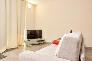 uma sala de estar com um sofá branco e uma TV em Tra la Rocca e il Lago em Angera