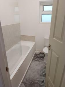 a white bathroom with a tub and a toilet at Modern 2 bedrooms Apartment- Ashton-Under-Lyne- Hosts 5 persons in Ashton under Lyne