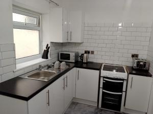 a white kitchen with a sink and a microwave at Modern 2 bedrooms Apartment- Ashton-Under-Lyne- Hosts 5 persons in Ashton under Lyne +13 photos