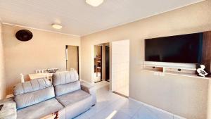 a living room with a couch and a flat screen tv at aconchegante com piscina e churrasqueira, pertinho da praia" in Itapoa