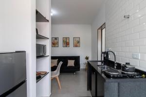 a kitchen with a counter top and a living room at 0804 Orquídea Studio Próx GRU e Estação Cecap in Guarulhos